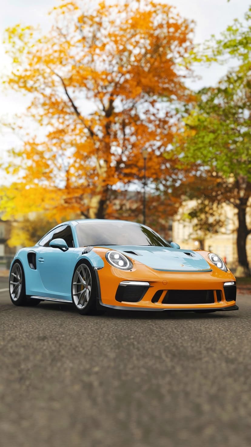 Porsche 911 GT3 RS in blue and orange paint drives on a road flanked by orange autumn forest foliage.