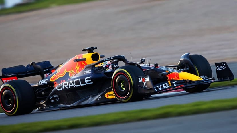 Red Bull Racing Formula 1 car with matte blue livery and yellow bull logo driving on a race track at sunset.