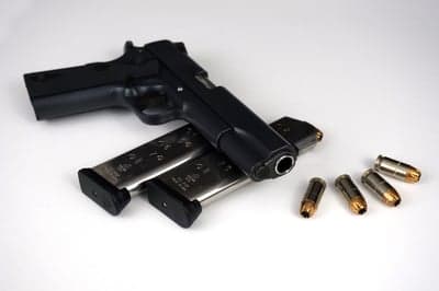 Black handgun with magazines and bullets on white