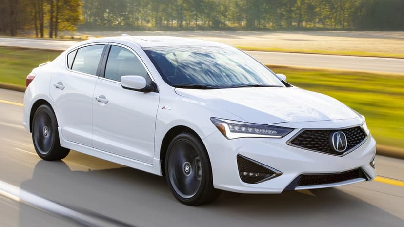 White Acura ILX A-Spec sedan driving on a sunlit highway with blurred wheels and a soft nature background.