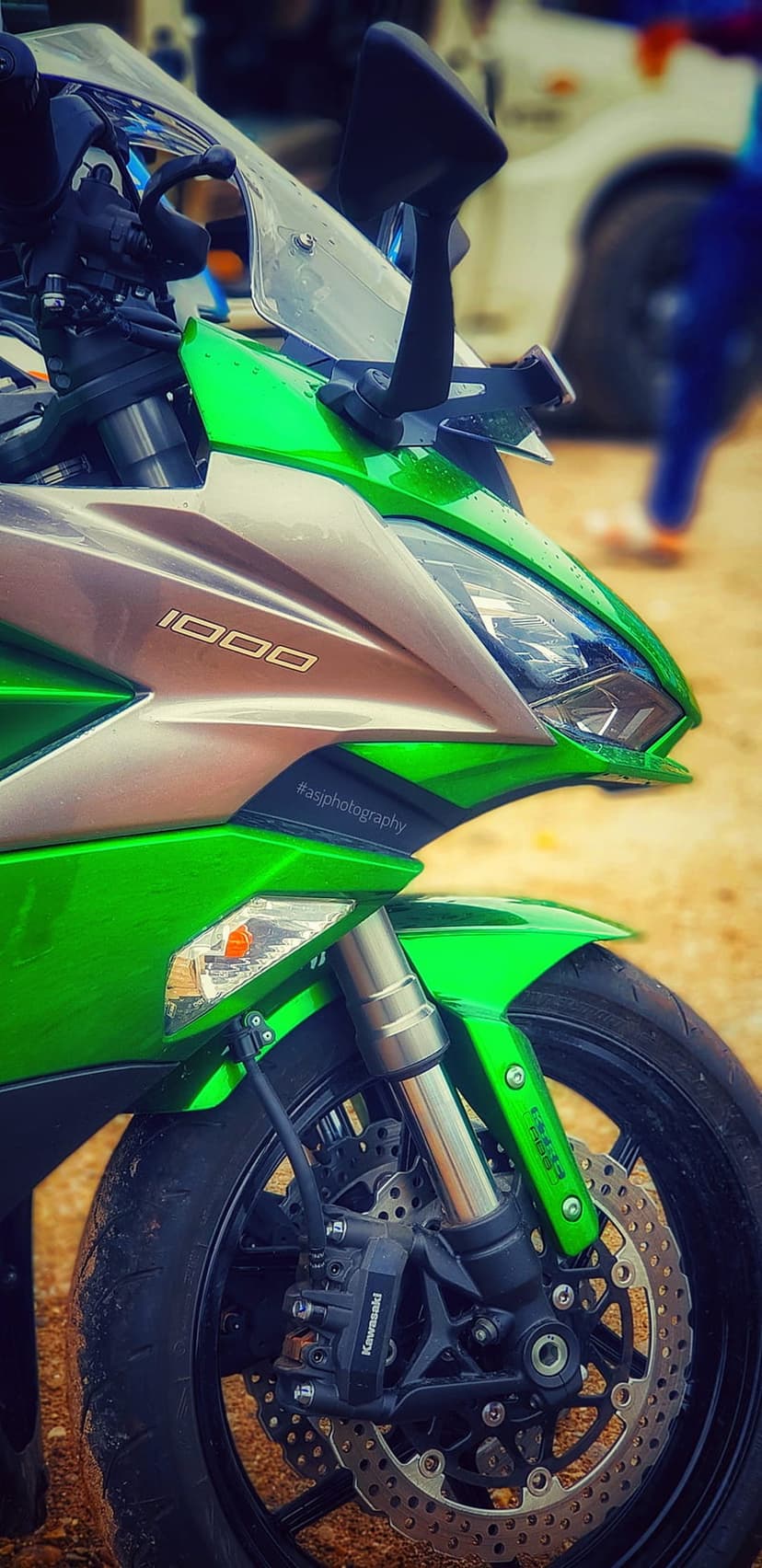 Green Kawasaki Ninja 1000 motorcycle front fairing with sharp headlights, metallic emblem, and disc brake wheel.