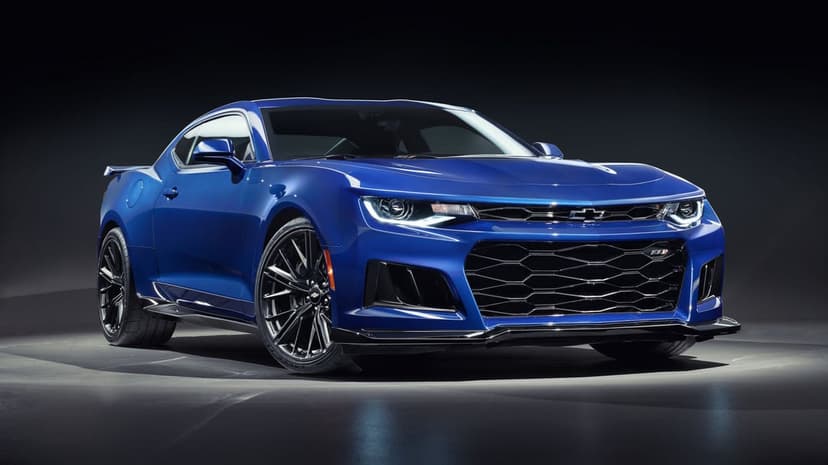 Blue Chevrolet Camaro ZL1 with LED headlights and black grille in a dark studio with dramatic lighting.