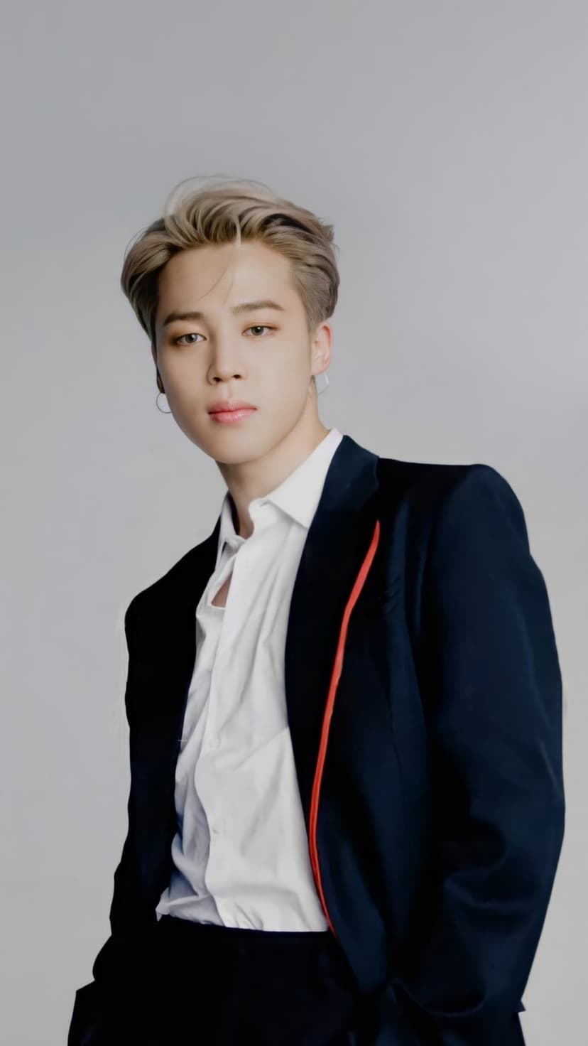 Park Jimin of BTS in a navy blazer and white shirt with styled blonde hair looking directly at the viewer.