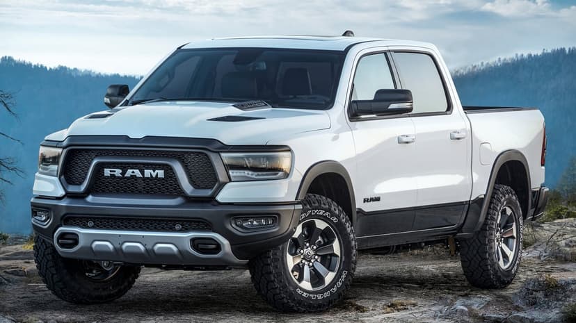 White Ram 1500 truck on a rocky cliff with a misty mountain background and large off-road tires.