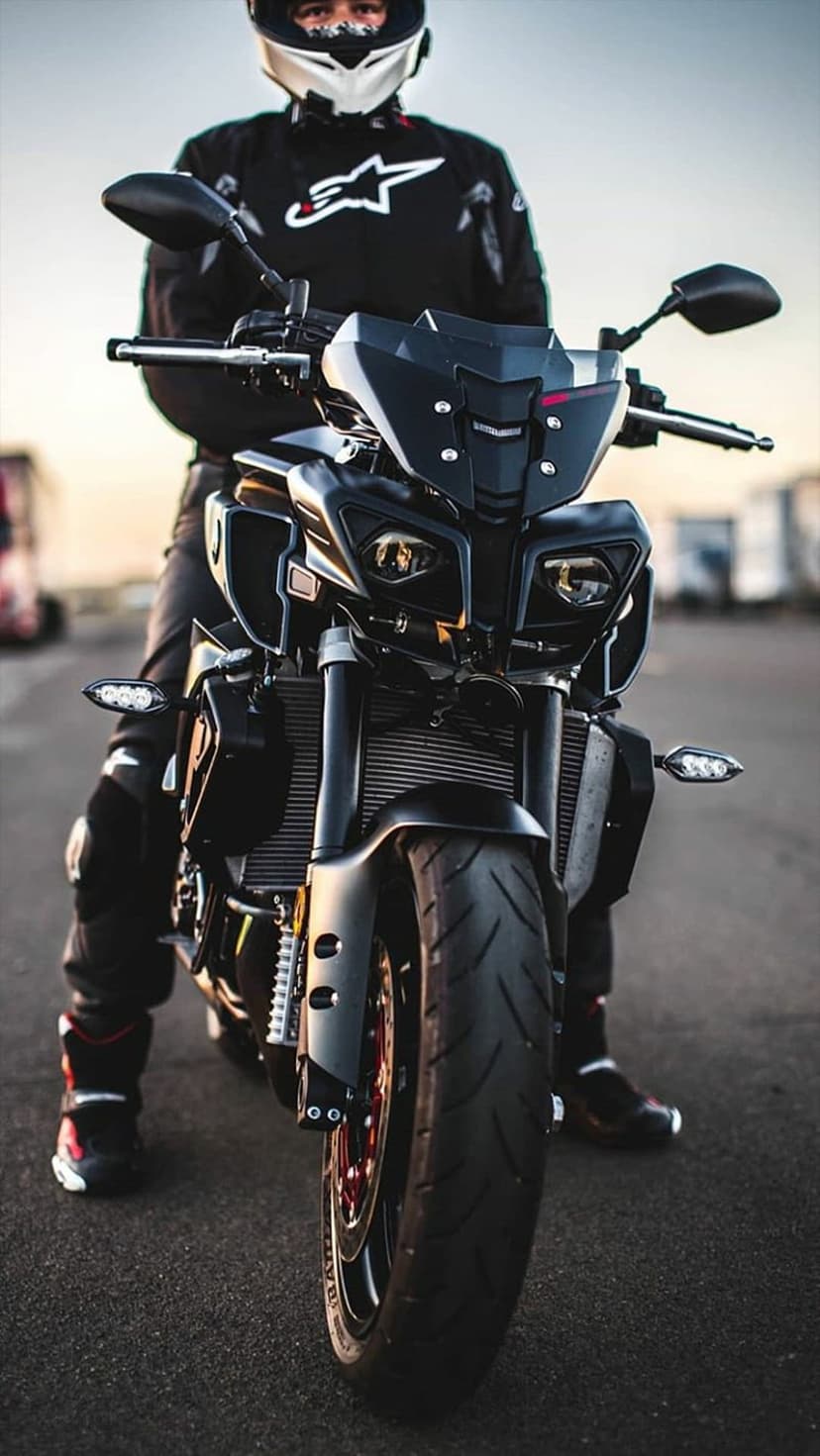 Rider in a black Alpinestars jacket and silver helmet sits on a black Yamaha motorcycle with twin headlights.