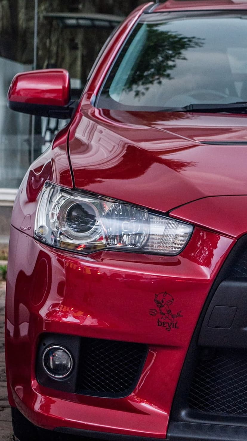 Red Mitsubishi Lancer Evolution X features a custom devil decal and glossy paint for a mobile screen backdrop.