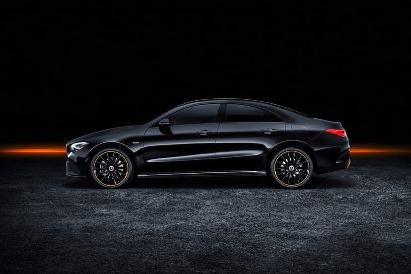Profile view of a black Mercedes-Benz CLA sedan with orange rim accents against a dark background and orange glow.