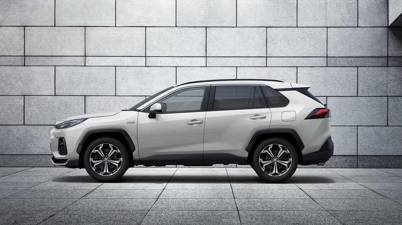 Side view of a white SUV parked in front of a grey rectangular tiled wall on a matching stone floor.