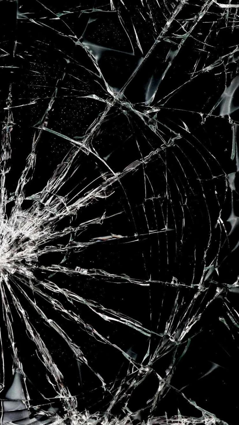 Shattered black glass surface with intricate white cracks radiating from a central impact point on a dark background.