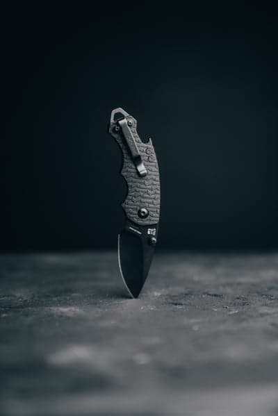 Black Folding Knife with Pocket Clip on Dark Surface