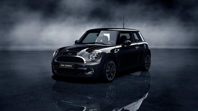 A black Mini Cooper S on a reflective floor against a dark foggy background with moody studio lighting.