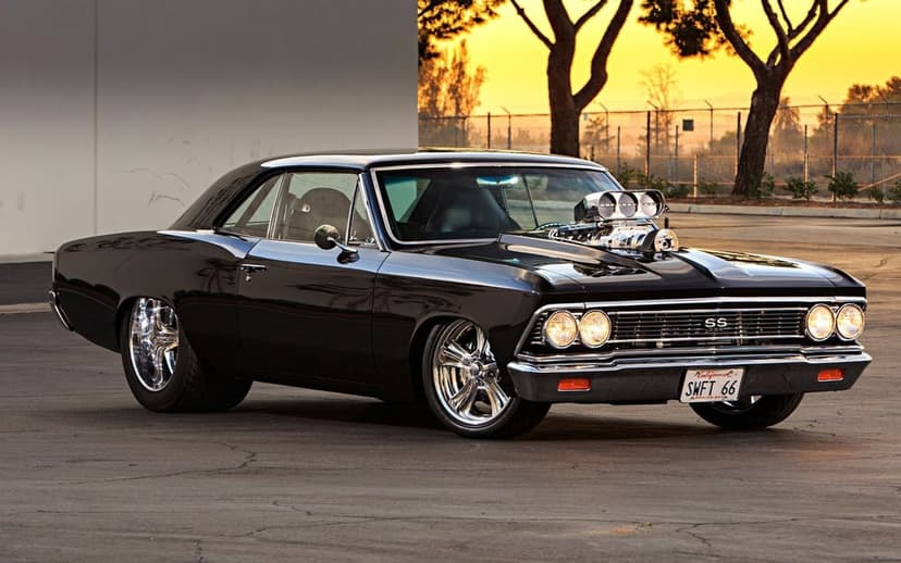 Black 1966 Chevelle SS muscle car with a supercharger engine and chrome wheels at sunset in a parking lot.
