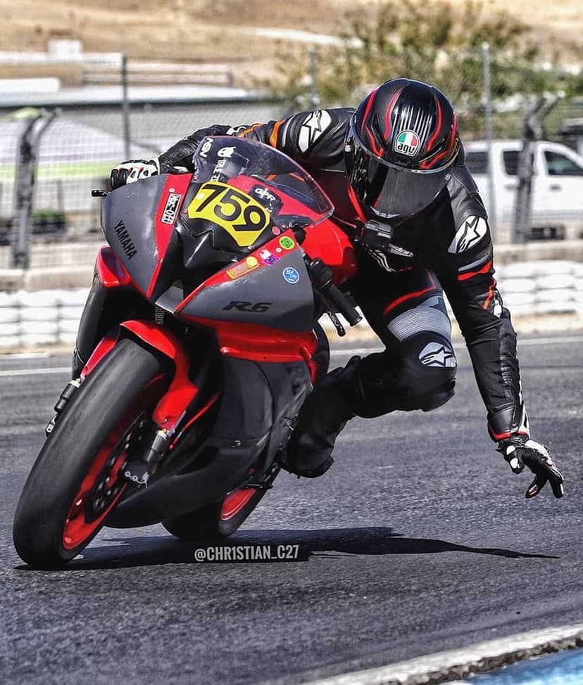 Yamaha R6 racer leaning low on a track turn wearing red and grey leathers with racing number 759 on the bike.