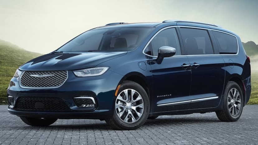 Dark blue Chrysler Pacifica Pinnacle parked on cobblestones against a misty, hazy green mountain landscape.