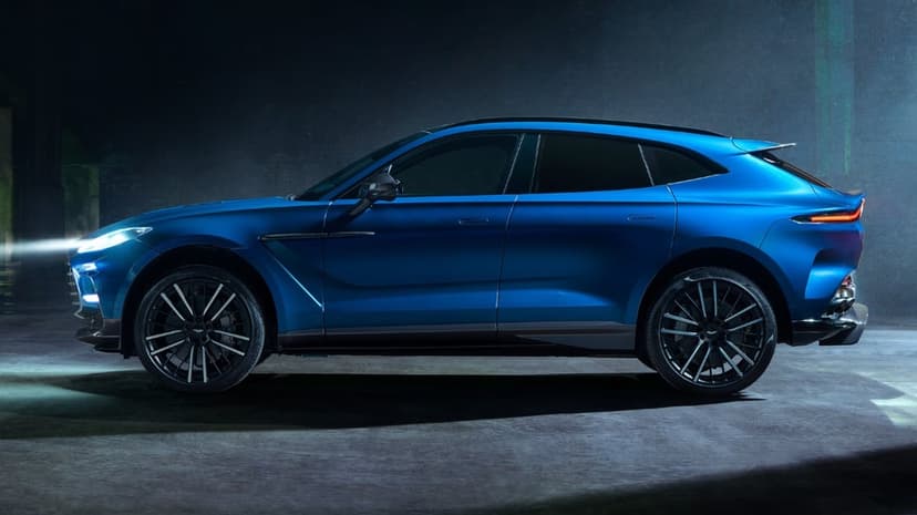 Blue luxury SUV side profile with glowing headlights against a dark atmospheric studio background.