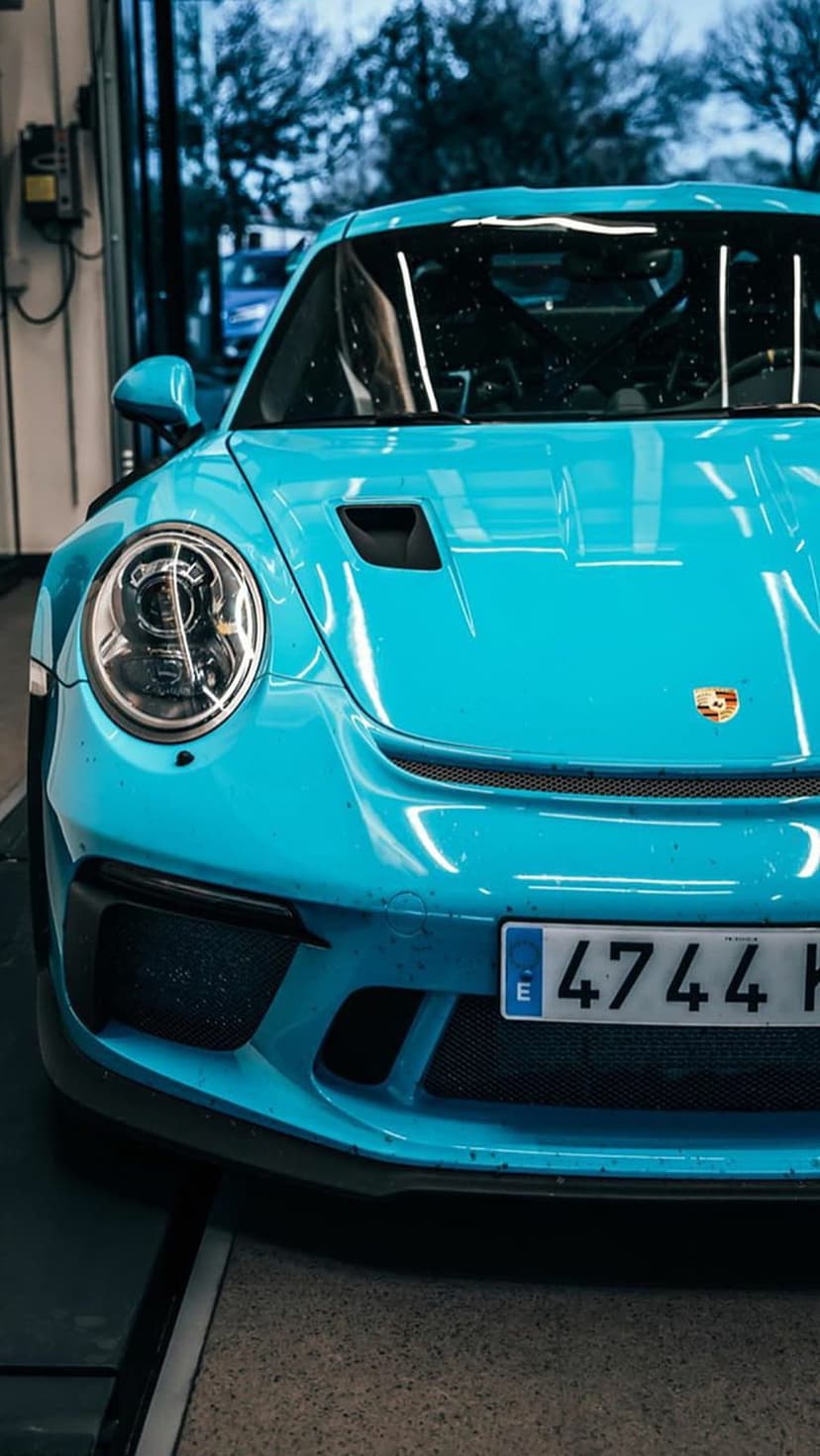 Blue Porsche 911 GT3 with signature headlights and air intakes captured in a sharp front-view perspective.