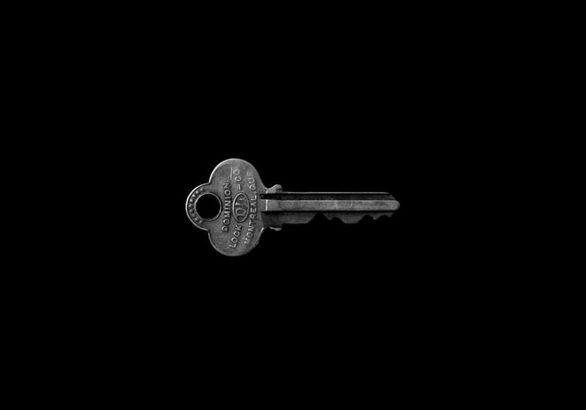 Silver Yale lock key with embossed text and serrated teeth centered against a solid black studio background.