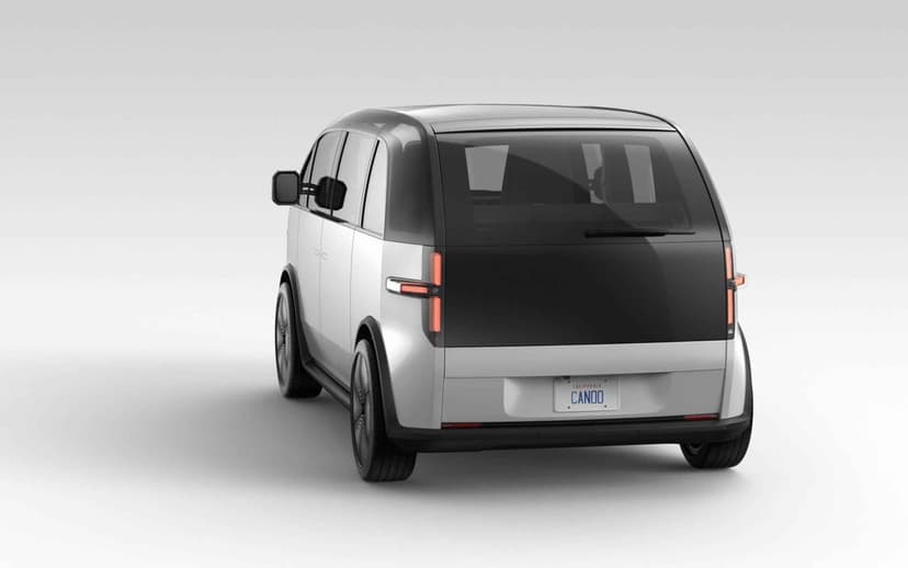 Rear view of a silver electric van with T-shaped taillights and black glass on a white studio background.