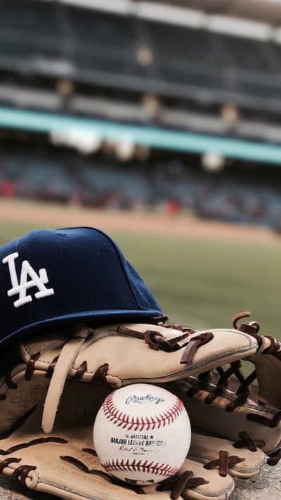A close-up shot of a baseball hat, glove, and ball on a field