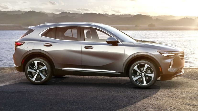 Silver SUV side profile parked near a calm lake at sunset with hazy mountains in the background.