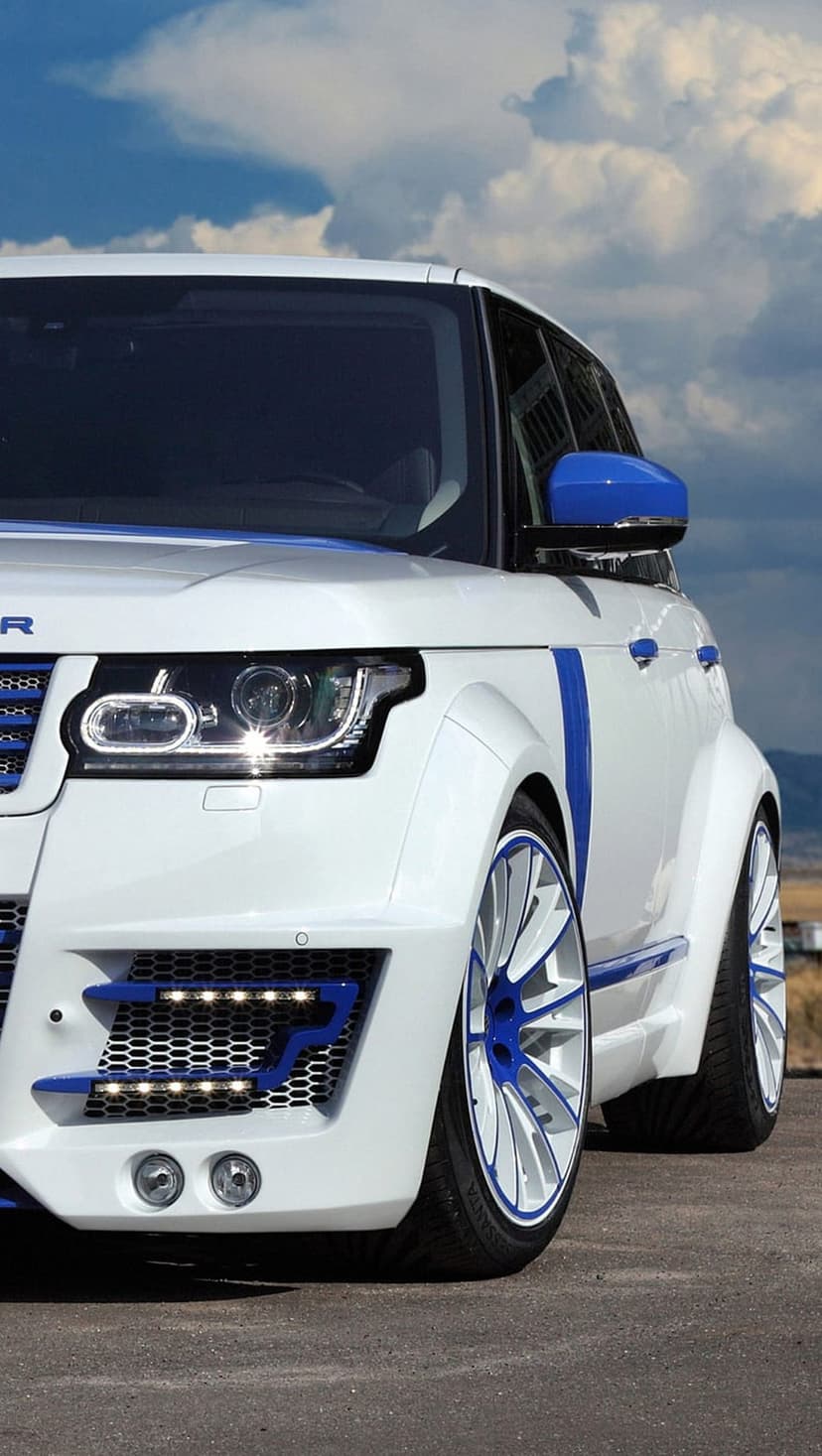 White Range Rover SUV with blue racing stripes and custom rims parked under a cloudy sky in a vertical shot.