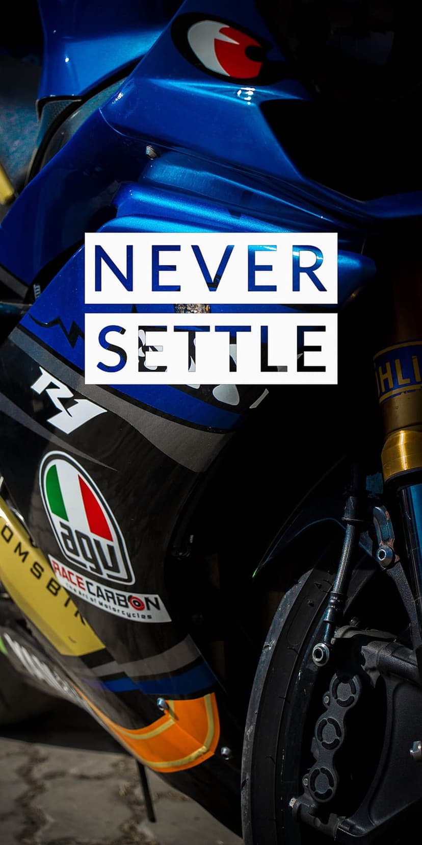 Blue and black motorcycle fairing with Never Settle text, AGV logo, and R1 branding in a tight vertical shot.
