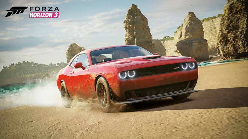 Red muscle car drifting on a sandy beach with tall rock pillars, turquoise ocean, and clear blue sky.