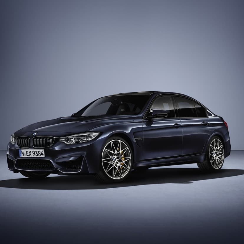 Dark blue BMW M3 sports sedan with silver wheels and gold calipers in a minimalist studio setting with soft lighting.