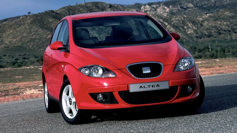Red SEAT Altea car on an asphalt road with rugged mountain hills and a clear blue sky in the background.