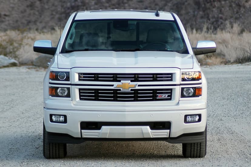 Front view of a white Chevrolet Silverado Z71 truck with chrome accents on a desert gravel road.