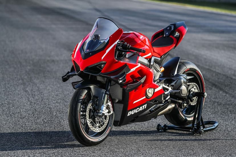 Red Ducati Superleggera V4 motorcycle parked on an asphalt racetrack with carbon fiber aerodynamic winglets.