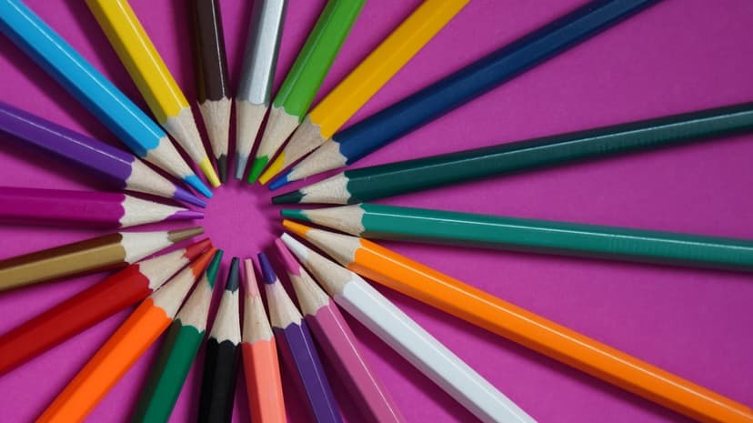 Sharpened colored pencils arranged in a circle with points meeting on a dark purple background for mobile screens.