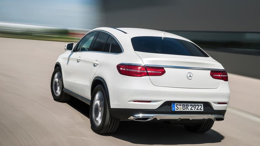 White Mercedes-Benz SUV coupe driving on a highway with intense motion blur and bright red LED taillights.