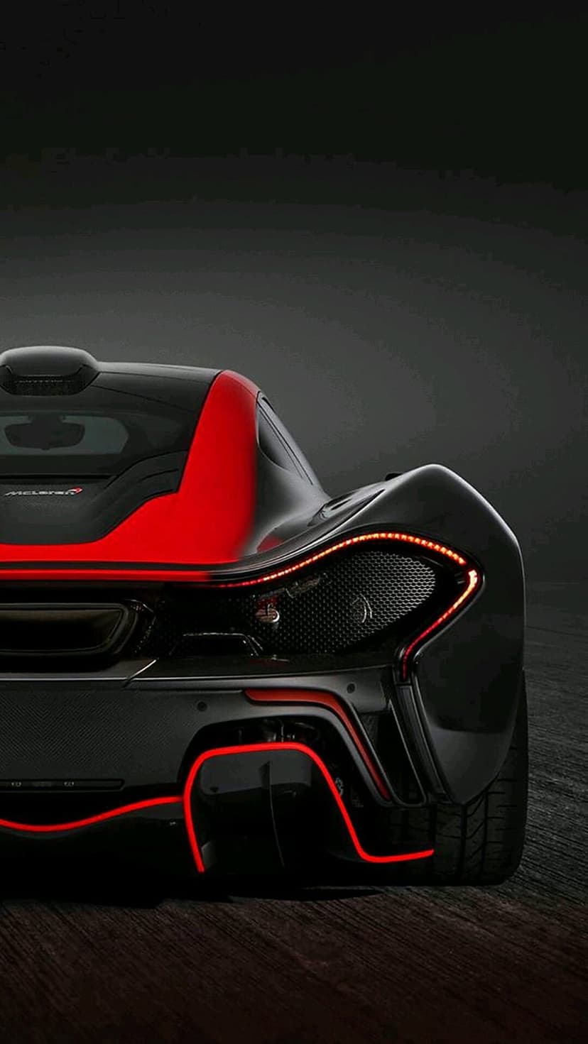 McLaren P1 rear view showing glowing red LED taillights and dark aerodynamic bodywork in a moody atmosphere.
