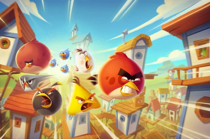 Angry Birds characters Red, Chuck, and Bomb fly forward through a birdhouse village in a bright blue sky.