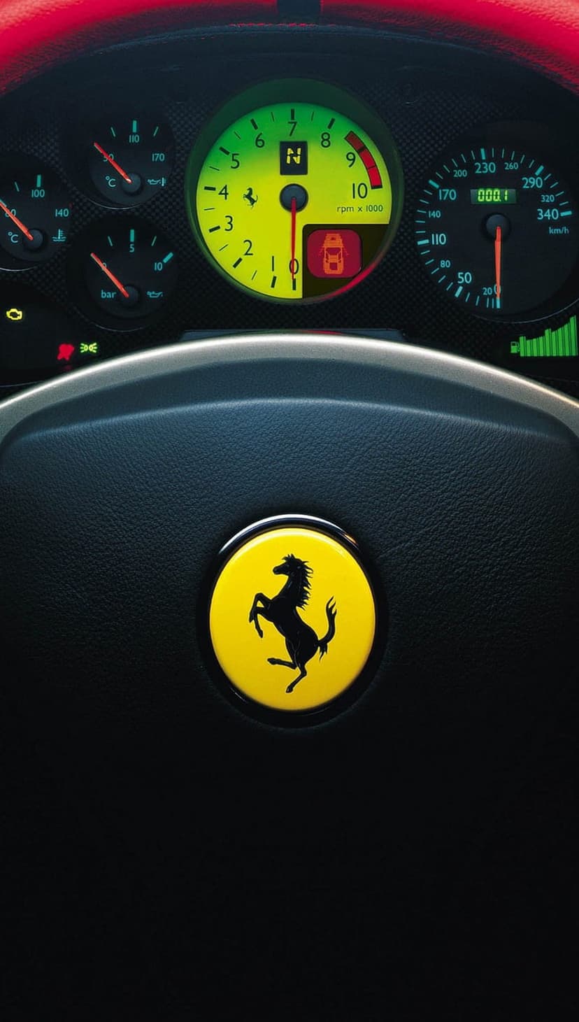 Ferrari steering wheel with a yellow horse logo and illuminated dashboard gauges in a luxury car interior.