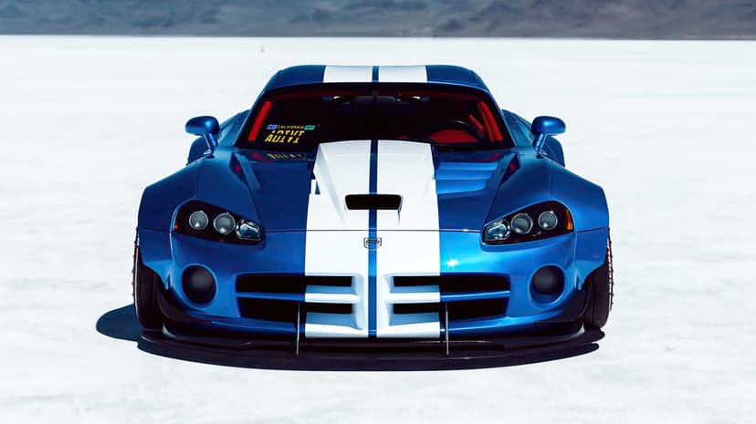 Front view of a blue widebody Dodge Viper with white racing stripes on flat white salt plains under bright sun.