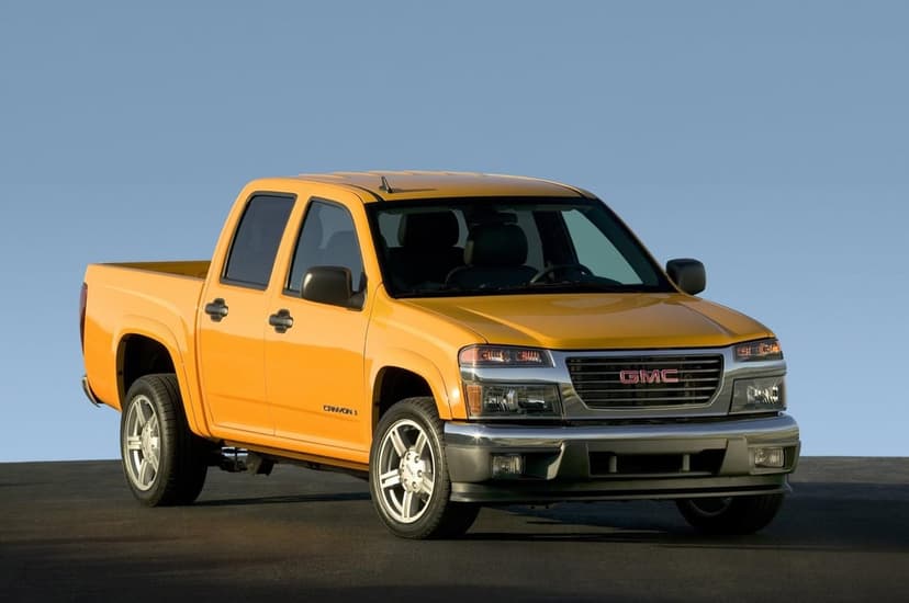 Yellow GMC Canyon pickup truck parked on asphalt under a clear blue sky with chrome accents and alloy wheels.