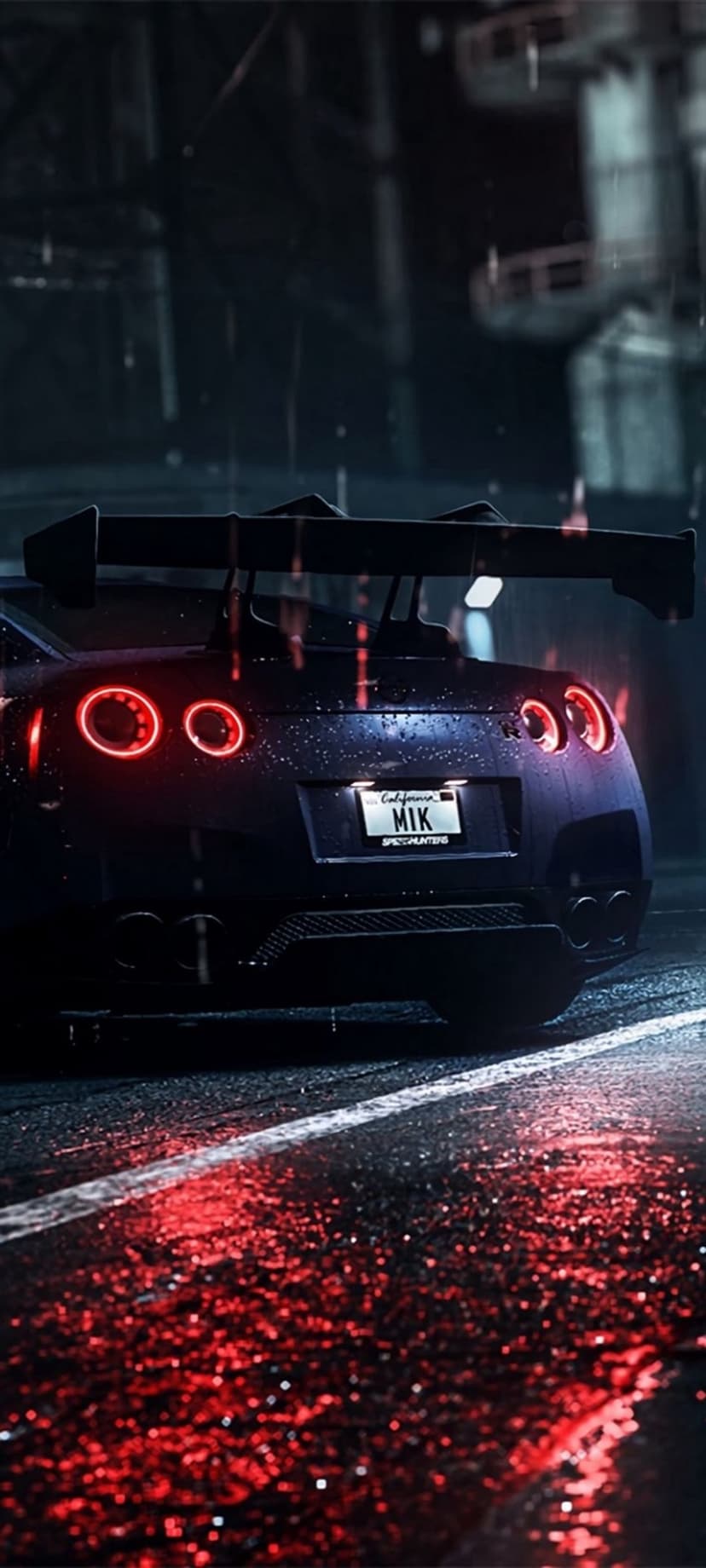 Nissan GT-R rear with glowing red taillights on a wet street at night reflecting on the dark pavement.