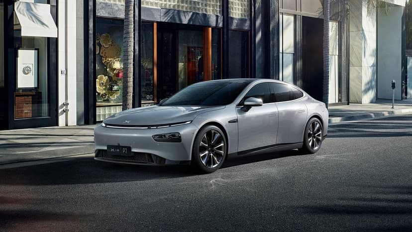 Silver Xpeng P7 electric sedan parked on a sunny city street with glass storefronts and palm trees.