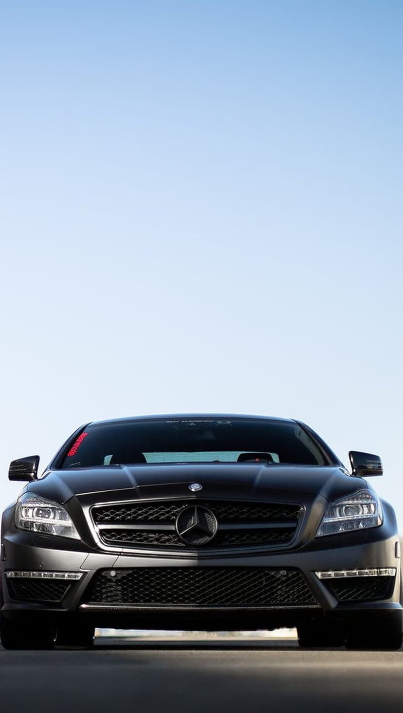 Mercedes-Benz CLS AMG front grille and headlights against a blue sky, showing the iconic silver star emblem.