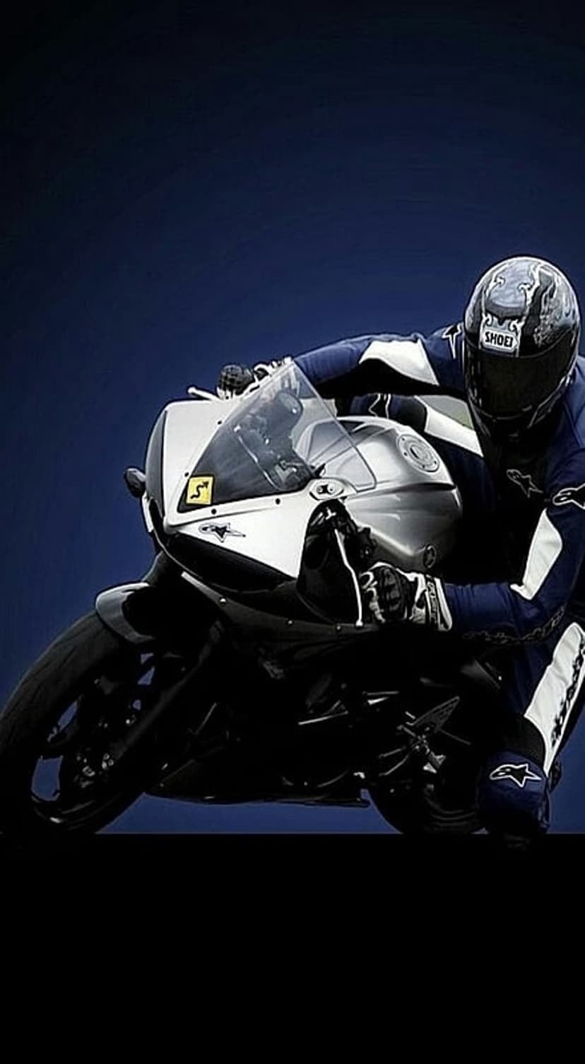 Motorcyclist in blue racing leathers leans a silver sportbike into a sharp asphalt turn on a sunny track day.