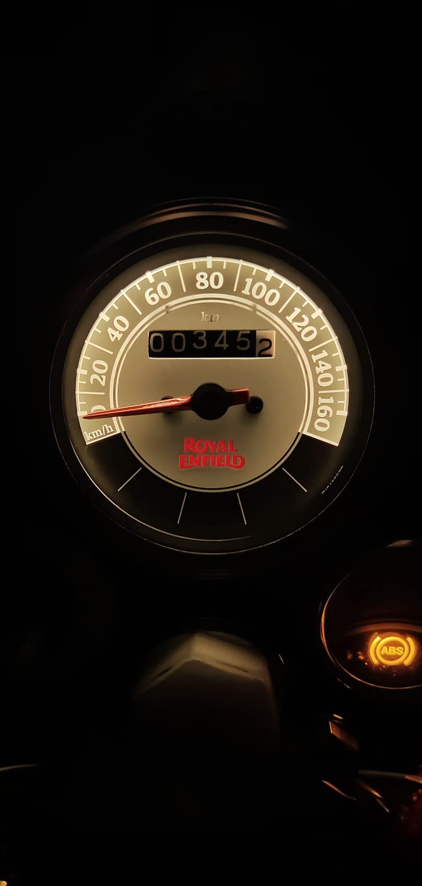 Royal Enfield speedometer with glowing orange ABS light and odometer display showing numerical distance readings.