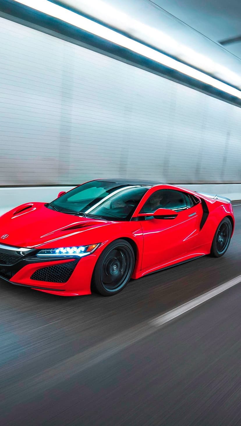 Red Acura NSX supercar speeds through a modern tunnel with motion blur in a portrait orientation shot.