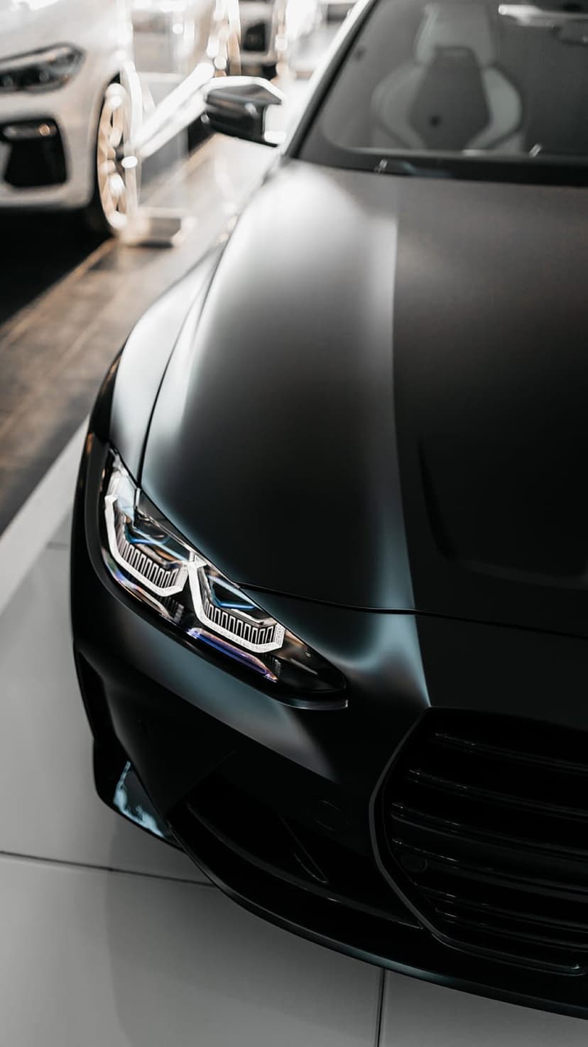 LED headlight of a matte black sports car showing intricate lens details and sharp front fascia geometry.