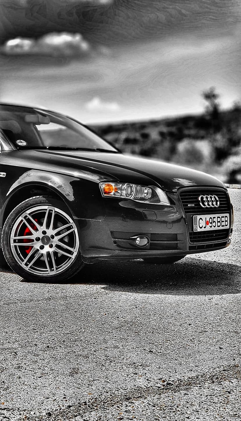 Black Audi A4 front wheel with red brake calipers, silver rings on the grille, and a clear glass headlight.