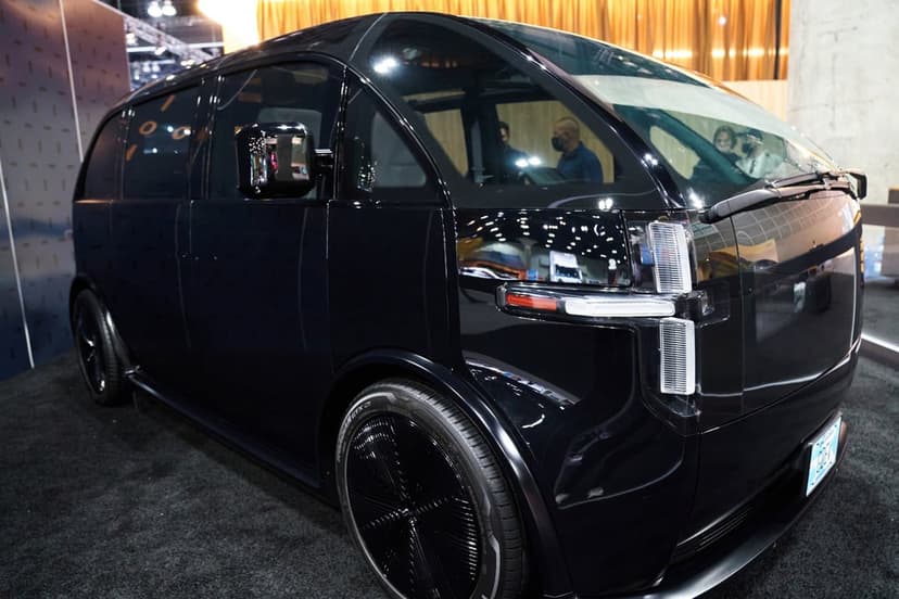 Modern black electric van with horizontal LED lights and glossy finish in an exhibition showroom.