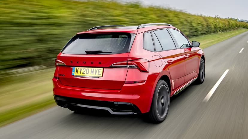 Red Skoda Kamiq SUV driving fast on a country road with motion blur and green hedges in the background.