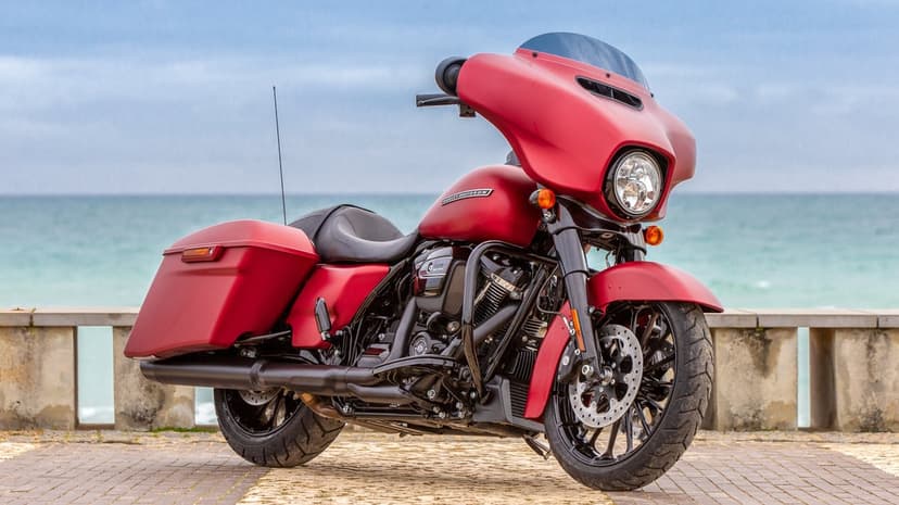 Matte red Harley-Davidson Street Glide Special parked on a coastal path with ocean waves in the background.