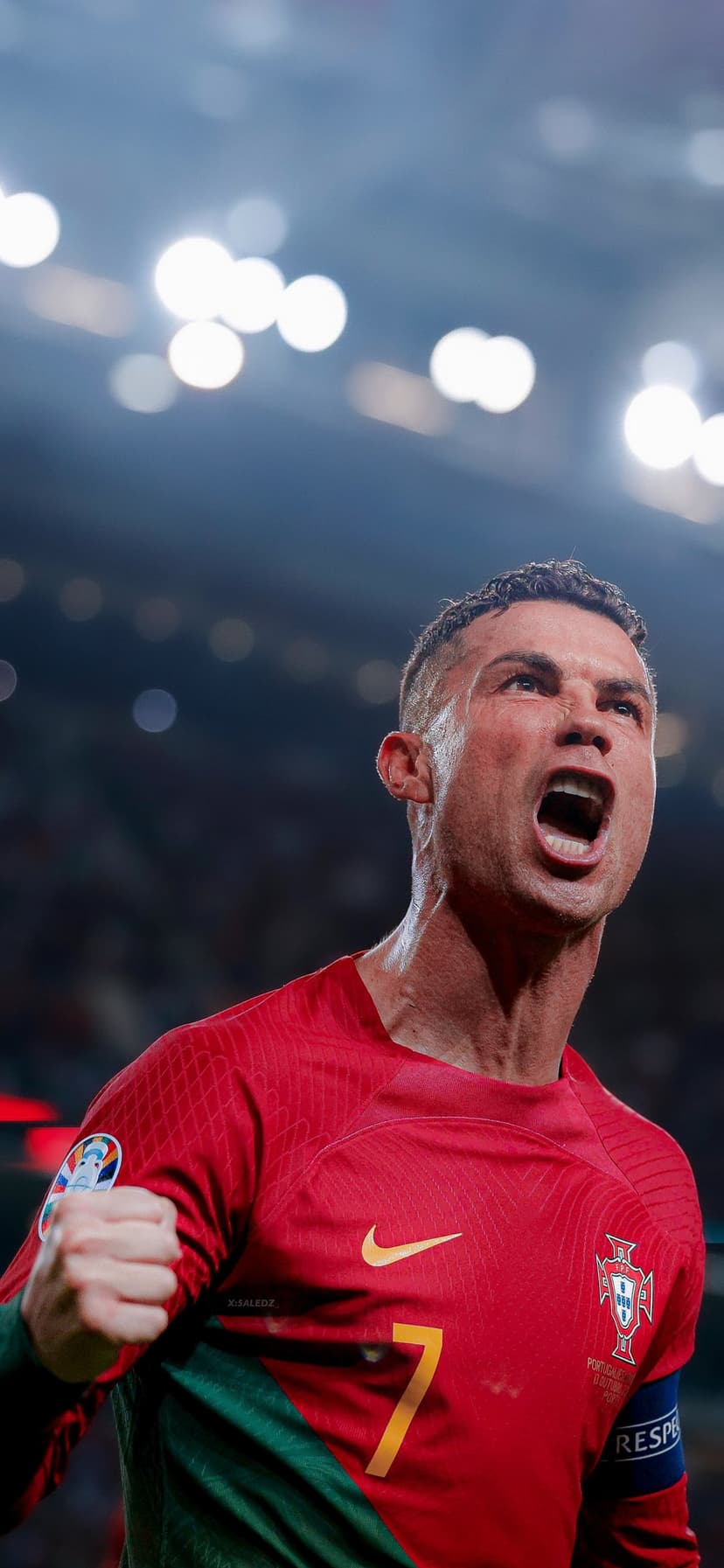 Cristiano Ronaldo shouts with a clenched fist while wearing a red Portugal number 7 jersey in a stadium.